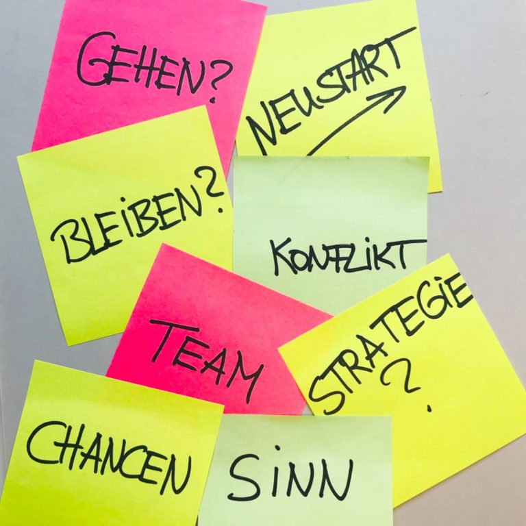 Haftnotizzettel in gelb, grün und pink; handschriftlich darauf Worte zum Thema Arbeit oder Arbeitssuche: Bleiben, Gehen, Neustart, Konflikt, Team, Strategie, Sinn, Chancen.